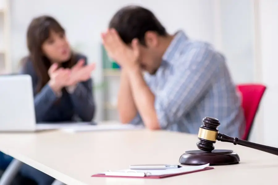 Stressed man and arguing woman in a legal setting with a gavel on the table, highlighting the impact of drug test results in legal disputes