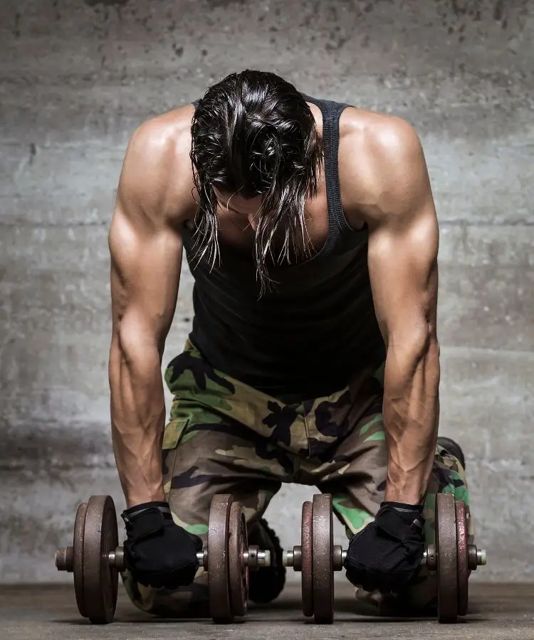 Weight training steroid abuse. Muscular man preparing to lift dumbbells during an intense workout session, highlighted by a raw, concrete background, emphasizing strength and athletic training
