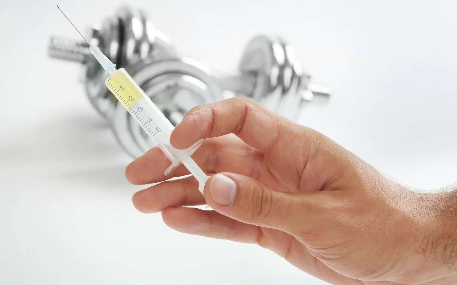 Close-up of a hand holding a syringe in a gym setting, highlighting the precision in steroid drug testing for athletes