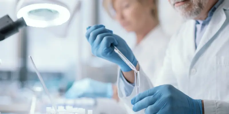 Senior laboratory scientists conducting precise drug testing in a modern lab, with a focus on teamwork and advanced scientific equipment.