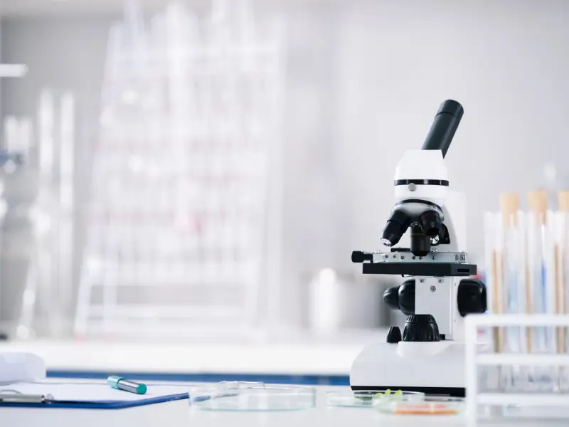 Modern laboratory with a high-powered microscope used for hair drug analysis, surrounded by test tubes and laboratory equipment, illustrating the precision of forensic drug testing