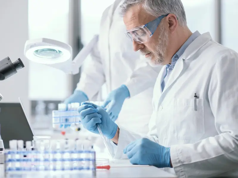 Laboratory scientist analysing hair sample vials under magnification, NATA-accredited hair testing process