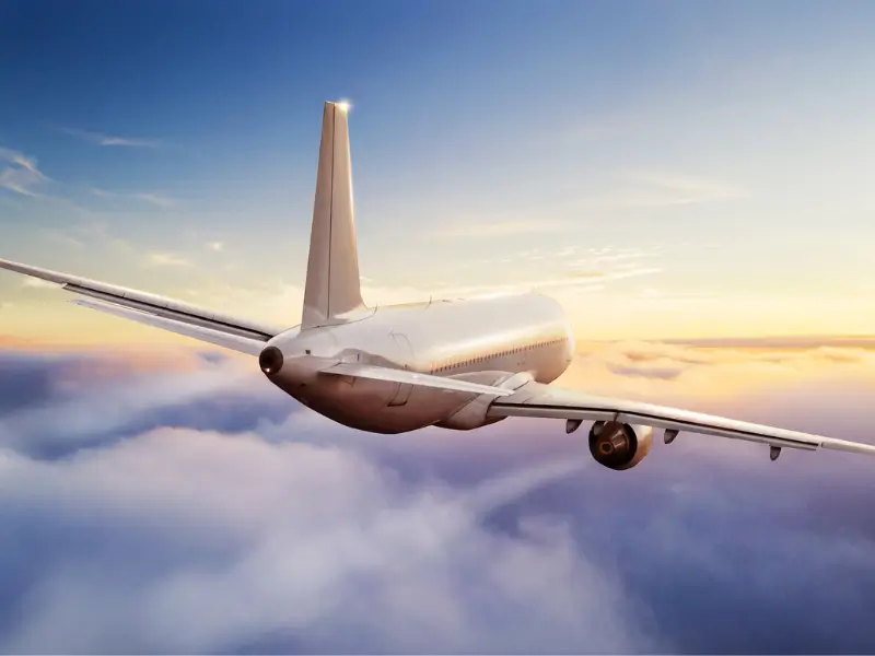 Commercial aircraft flying above the clouds at sunset, safety-sensitive aviation activity