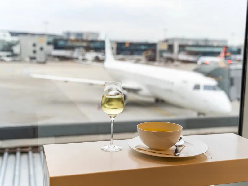 irport departure lounge with wine and refreshments, aircraft visible through the window, representing the aviation environment covered by CASA drug and alcohol testing rules for pilots