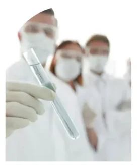 Lab scientist holding a test tube in focus, with a team of colleagues in the background, in a sterile environment for precise hair drug and alcohol testing